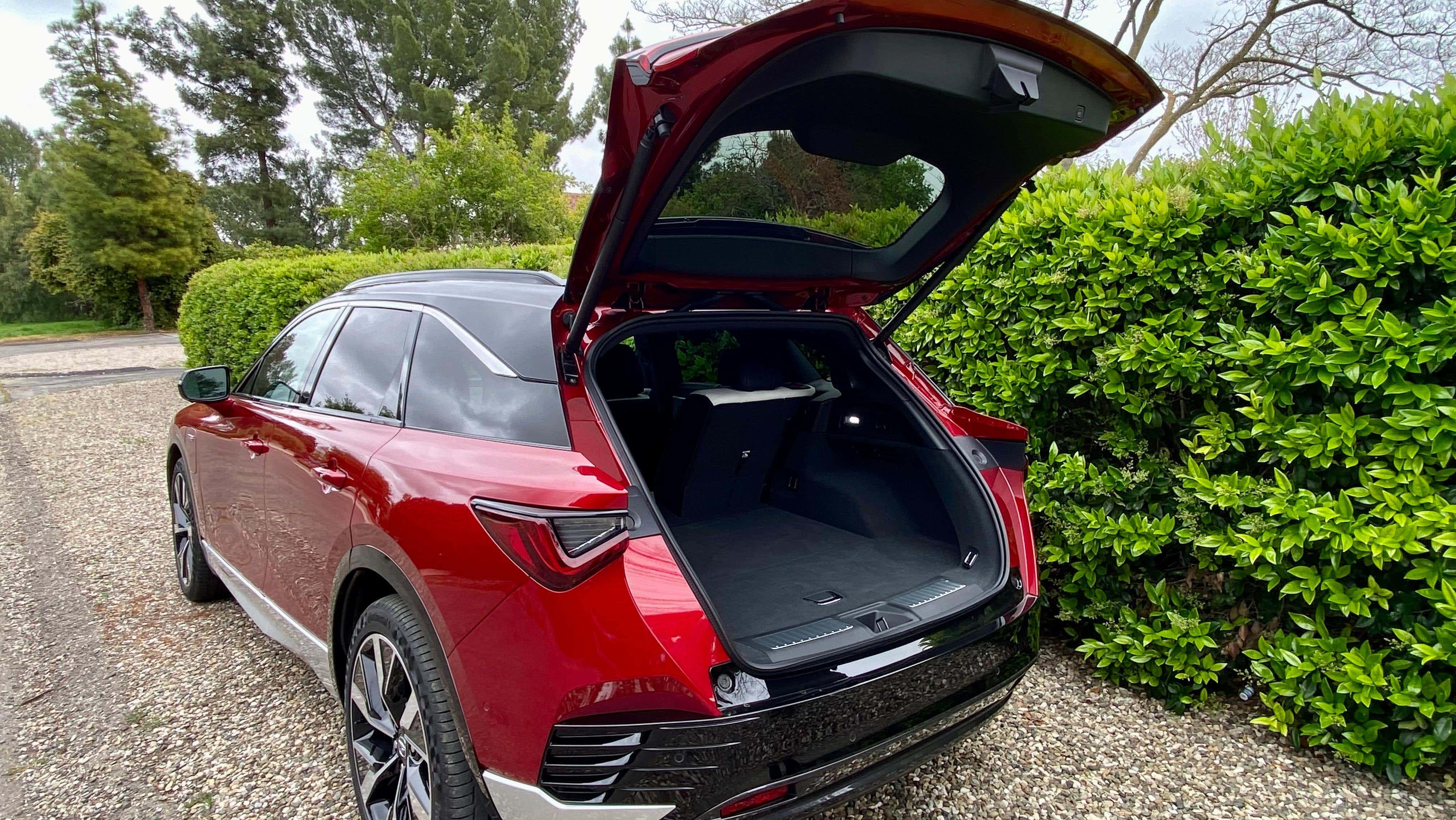 A photo of the red ZDX Type S with the trunk open, parked in front of a hedge